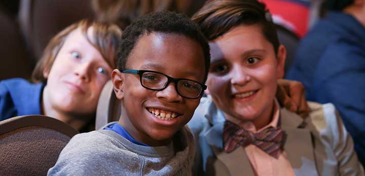 Three young boys smile for the camera at a concert