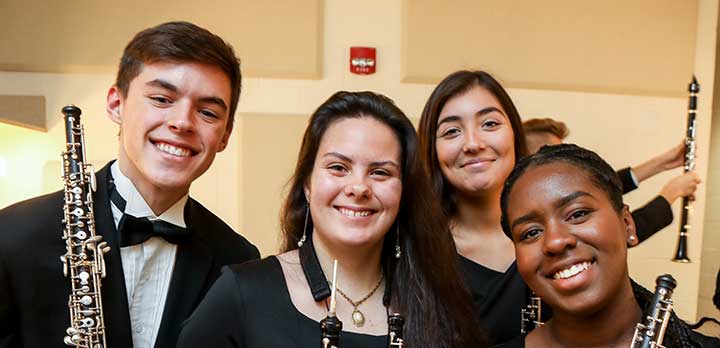 4 youth orchestra members smile for the camera